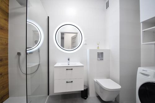 a white bathroom with a toilet and a mirror at Apartamenty Międzywodzie Plażowa Park in Międzywodzie