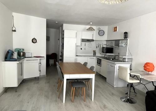 eine Küche mit weißen Schränken und einem Tisch mit Stühlen in der Unterkunft bel appartement climatisé centre in Albi