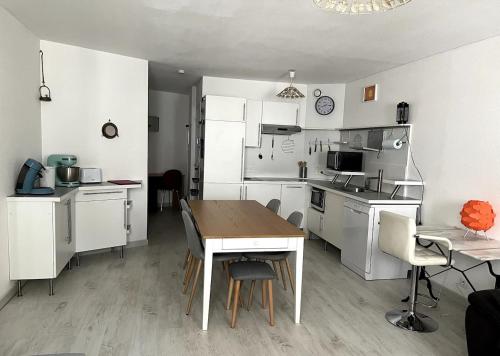une cuisine avec des armoires blanches et une table avec des chaises dans l'établissement bel appartement climatisé centre, à Albi