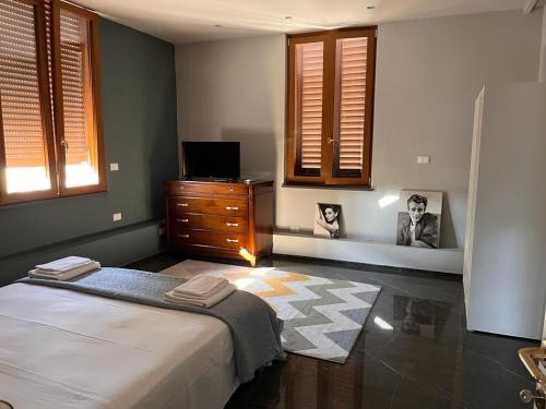 a bedroom with a bed and a dresser and windows at Casa Cavour in Montecatini Terme