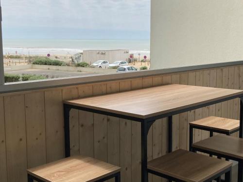 a table and two stools with a view of the beach at Le Petit Large T2 - vue sur mer in Saint-Hilaire-de-Riez