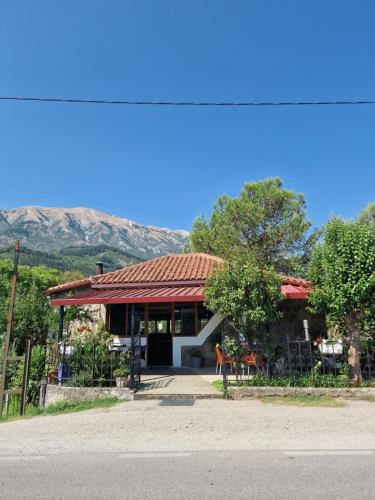 a house with a red roof with a mountain in the background at Guest House KrisHen in Përmet