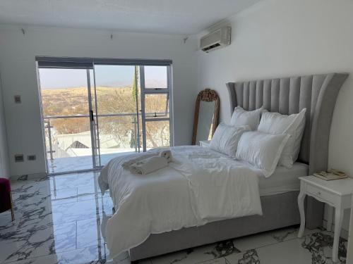 a bedroom with a large bed with a large window at Avis sunrise view in Windhoek