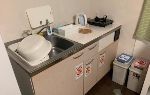 a small kitchen with a sink and a microwave at Oyado Kinokuniya Daikokumachi in Nagasaki