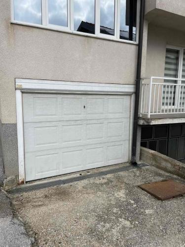 a white garage door on the side of a house at Apartment Vil in Slatina