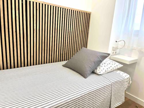 a bed with a striped headboard and a pillow on it at Acogedor apartamento 5 personas in Valencia