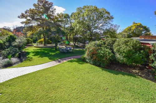 a park with green grass and trees and a walkway at River Country Inn in Moama