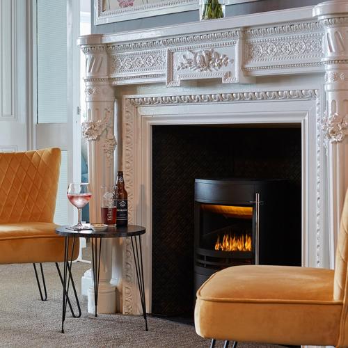 a living room with a fireplace and a table with wine glasses at Luccombe Manor Country House Hotel in Shanklin