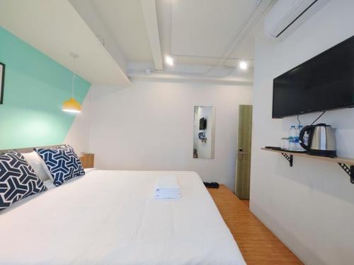 a bedroom with a white bed and a flat screen tv at Ostay Asoke Bangkok in Makkasan