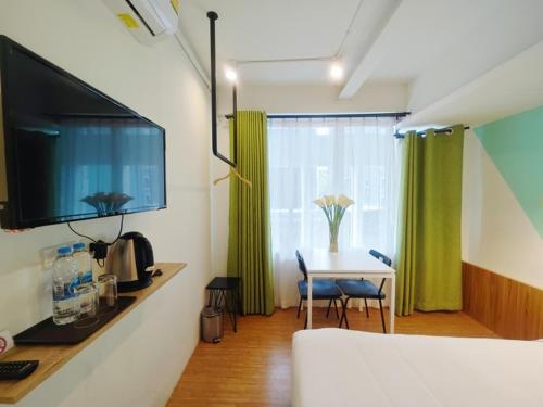 a room with a table and a television and a table and chairs at Ostay Asoke Bangkok in Makkasan