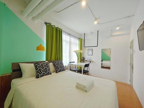 a bedroom with a large white bed and a table at Ostay Asoke Bangkok in Makkasan