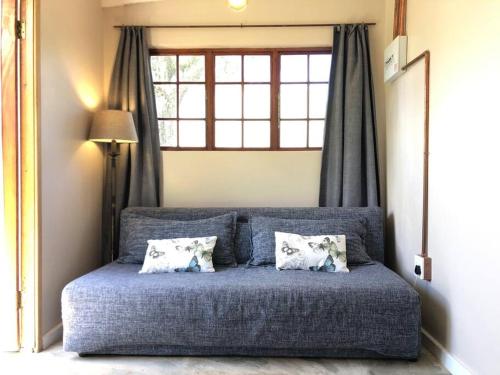 ein blaues Bett mit zwei Kissen und einem Fenster in der Unterkunft Modern Industrial Cottage in Kingsborough