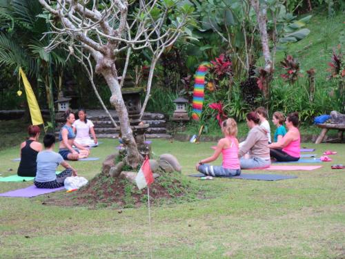 a group of people sitting around a tree in the grass at Kebun Villa, Belimbing, Bali in Tabanan