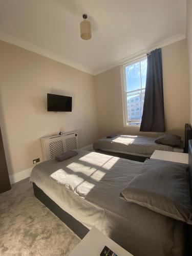 a bedroom with two beds and a tv on the wall at South Chelsea Room London in London
