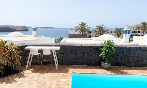 eine Terrasse mit einem Tisch, Stühlen und Meerblick in der Unterkunft Villa Liv in Playa Blanca