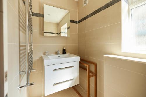 uma casa de banho com um lavatório e um chuveiro em The Kilburn Crib - Stunning 3BDR Flat em Londres
