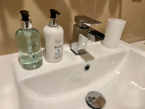 a bathroom sink with two soap bottles on it at Central Apartment Linlithgow in Linlithgow