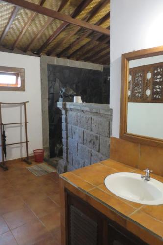 a bathroom with a sink and a brick fireplace at Kebun Villa, Belimbing, Bali in Tabanan