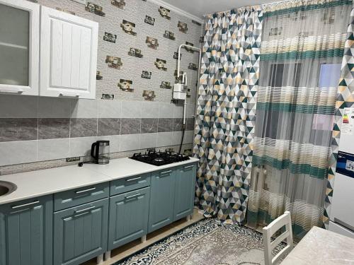 a kitchen with blue cabinets and a shower curtain at Гостевой Дом in Qyzylorda
