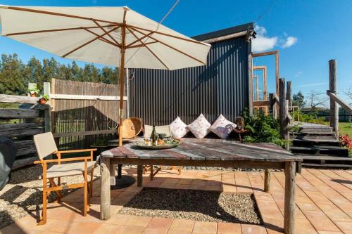 a wooden table with an umbrella on a patio at FreeFall Hut in Hastings