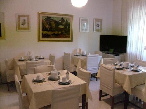 a dining room with white tables and chairs and a television at B&B Fragus e Saboris de Sardigna in Sadali