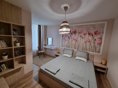 um quarto com uma cama e um quadro de flores cor-de-rosa em Apartment Polina - 2BD Next to Sea Garden Varna em Varna City