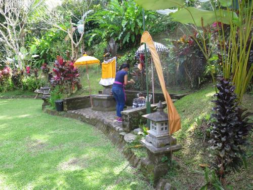 a woman standing under an umbrella in a garden at Kebun Villa, Belimbing, Bali in Tabanan