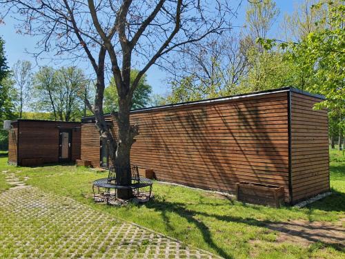 a small wooden cabin with a tree in the yard at Lavečka u Valtic in Valtice