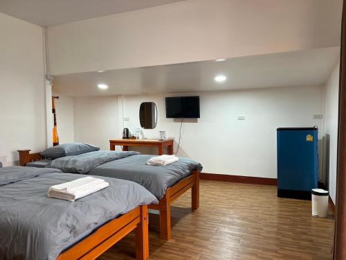 a room with two beds and a tv in a room at บ้านสวนมะม่วงรีสอร์ท 