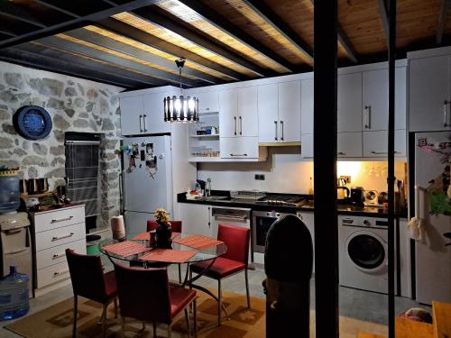 eine Küche mit weißen Schränken sowie einem Tisch und Stühlen in der Unterkunft Çiftlik ve Dağ evi Kemer - Canerbey in Kemer