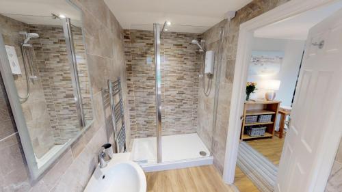 La salle de bains est pourvue d'une douche et d'un lavabo blanc. dans l'établissement Avocet at Leigh Cottages, à Seaton