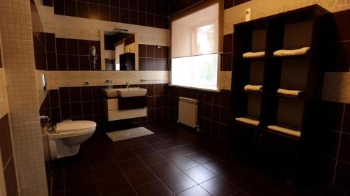 a bathroom with a toilet and a sink and a window at Hotel Fessla in Kostanay