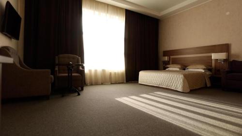 a bedroom with a bed and a large window at Hotel Fessla in Kostanay