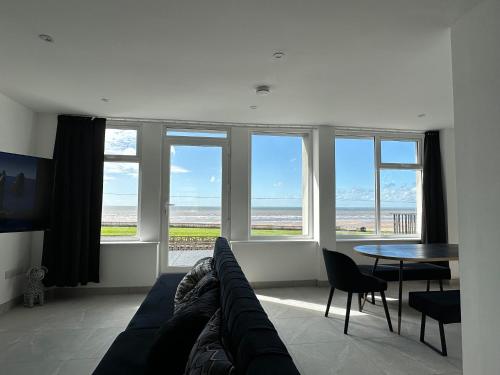 a living room with a couch and a table and windows at Queens Apartment 1 in Blackpool