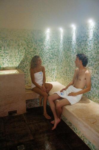 a man and woman sitting on a bed in a tub at Hotel Lovere Resort & Spa in Lovere
