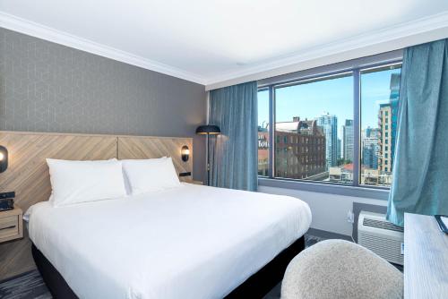 a hotel room with a bed and a large window at Sandman Hotel Vancouver Downtown in Vancouver