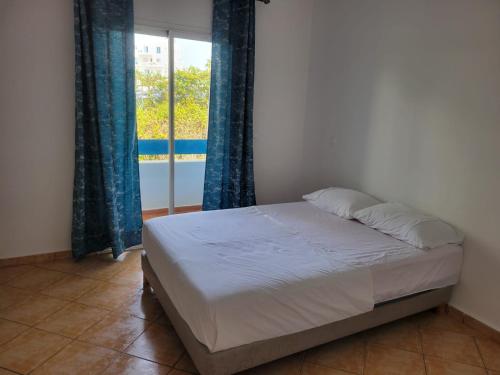 1 dormitorio con 1 cama y una ventana con cortinas azules en SMIR PARK, en Marina Smir