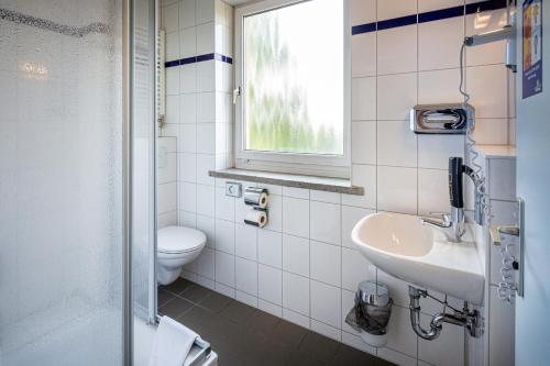 ein Bad mit einem Waschbecken, einem WC und einem Fenster in der Unterkunft a&o Weimar in Weimar