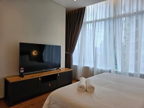a bedroom with a bed and a flat screen tv at Sky Suites KLCC by Asiapex in Kuala Lumpur