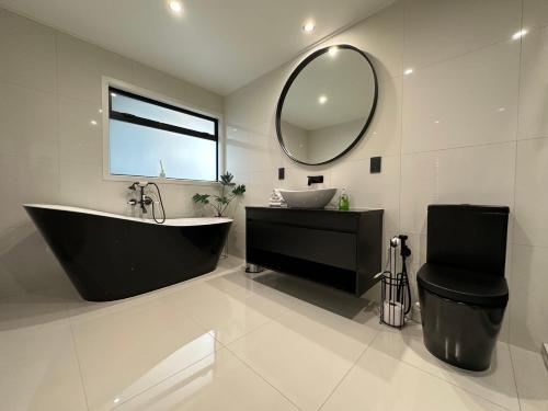 a bathroom with a tub and a sink and a mirror at A Dreamed Home Away From Home in Rotorua