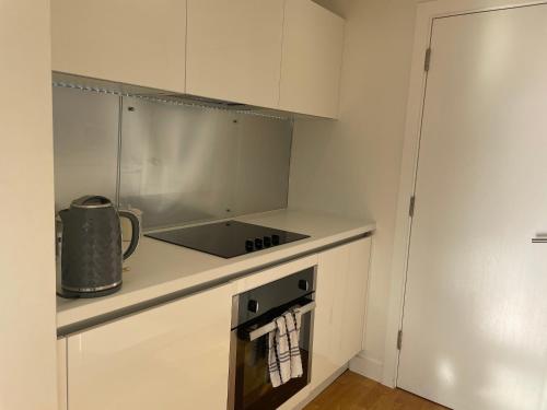a small white kitchen with a stove top oven at The Signature Suite in Bradford