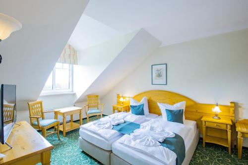 ein Hotelzimmer mit einem Bett, Tischen und Stühlen in der Unterkunft Ferien Hotel Fläming in Niemegk