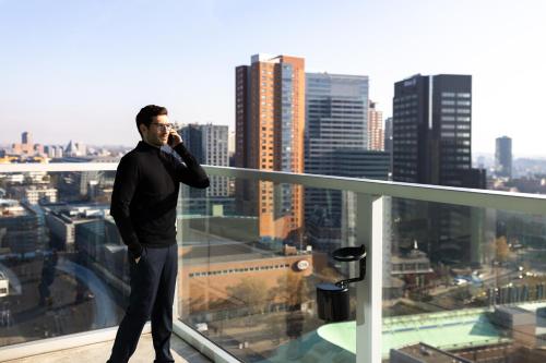 a man talking on a cell phone on top of a building at Urban Residences Rotterdam in Rotterdam