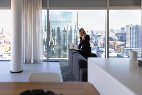 a woman sitting on a couch talking on a cell phone at Urban Residences Rotterdam in Rotterdam