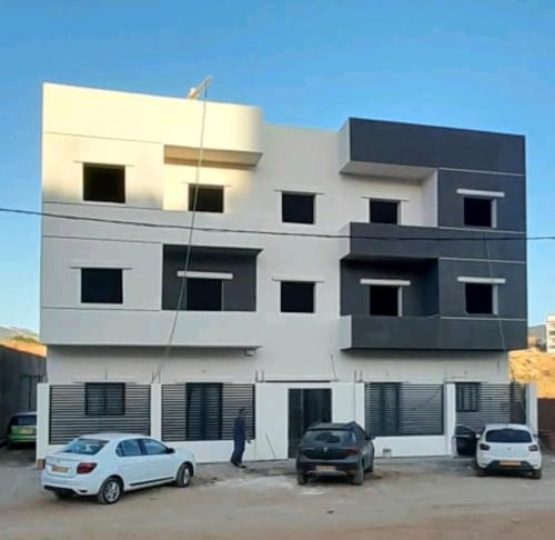 a building with two cars parked in front of it at Golden GbS in Skikda