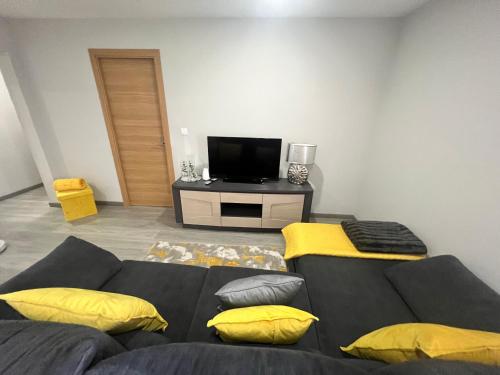 a living room with a black couch and yellow pillows at Casa da Portela in Paredes de Coura