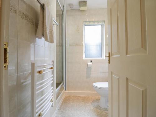 La salle de bains blanche est pourvue de toilettes et d'une fenêtre. dans l'établissement Beech Timber Lodge, à Keswick
