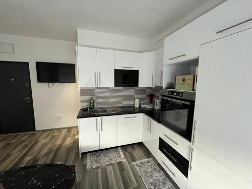 a kitchen with white cabinets and black appliances at Stan na dan, Pazar Tuzla - centar grada in Tuzla