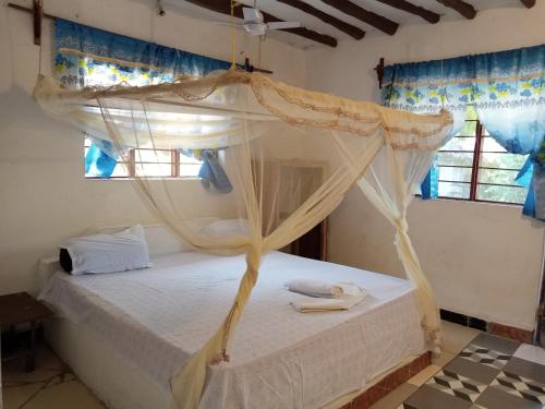 a bedroom with a canopy bed with two towels on it at Bwejuu Garden View Bungalows in Kiganga