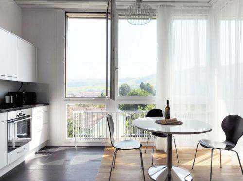 cocina con mesa, sillas y ventanas en Nest - Baarerstrasse 82, en Zug